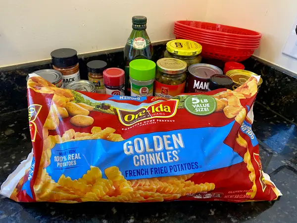 A bag of golden crinkle cut fries in front of a row of spices