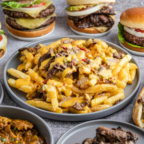 a plate of loaded fries surrounded by burgers