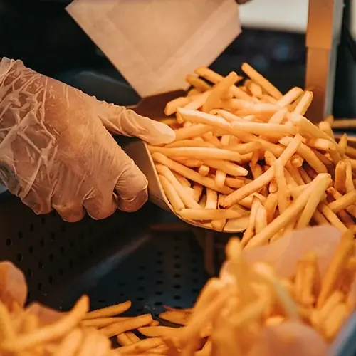 fresh fries being scooped into a container