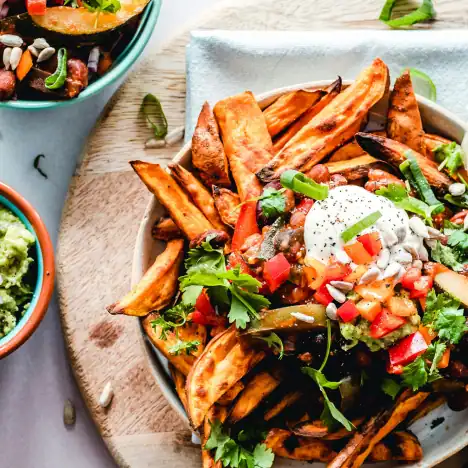 Some baked fries topped with cilantro, tomato, green onion, and Greek yogurt